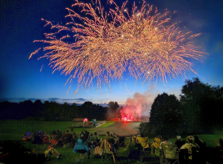 Fireworks in the sky with spectators watching.