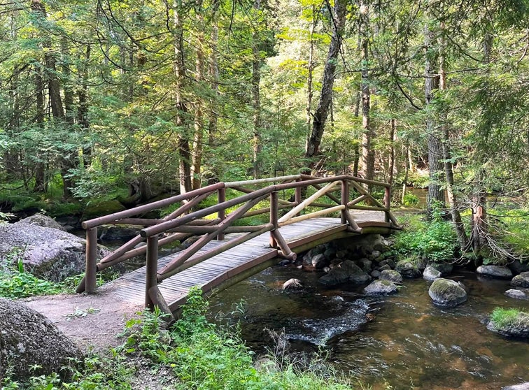 Photo of a wood pedestrian bridge over a river.